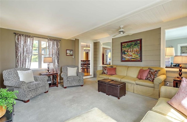 living area featuring ceiling fan with notable chandelier and carpet floors