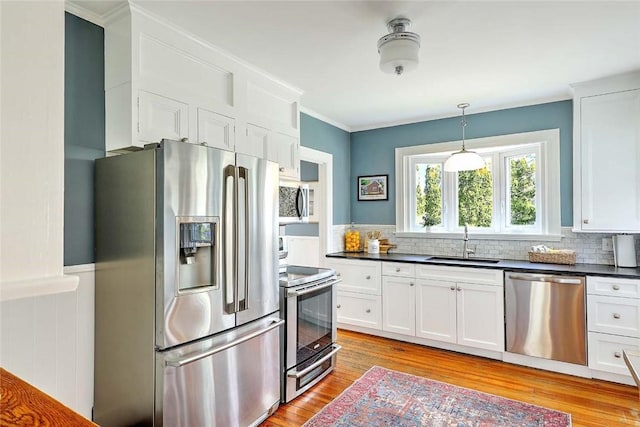 kitchen featuring a sink, dark countertops, light wood-style floors, white cabinetry, and stainless steel appliances