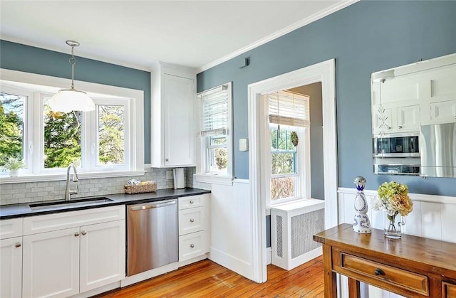 kitchen featuring white cabinets, a sink, appliances with stainless steel finishes, dark countertops, and radiator