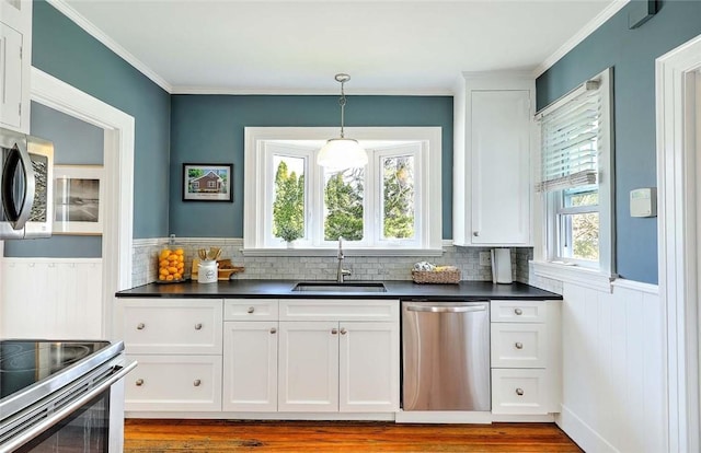 kitchen featuring stainless steel appliances, a healthy amount of sunlight, a sink, and dark countertops
