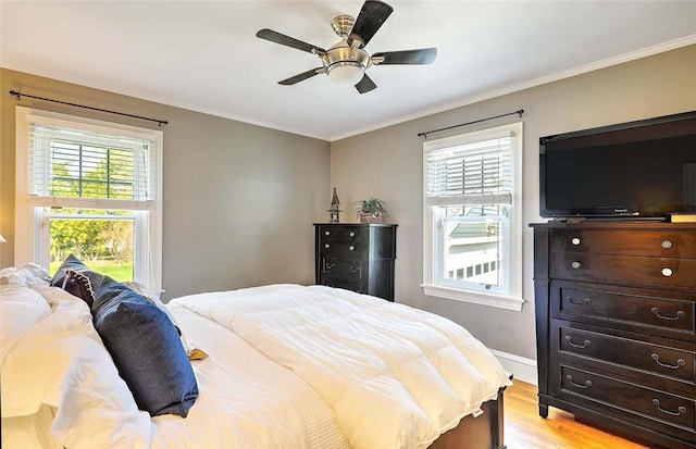 bedroom featuring ornamental molding, light wood-style flooring, multiple windows, and baseboards
