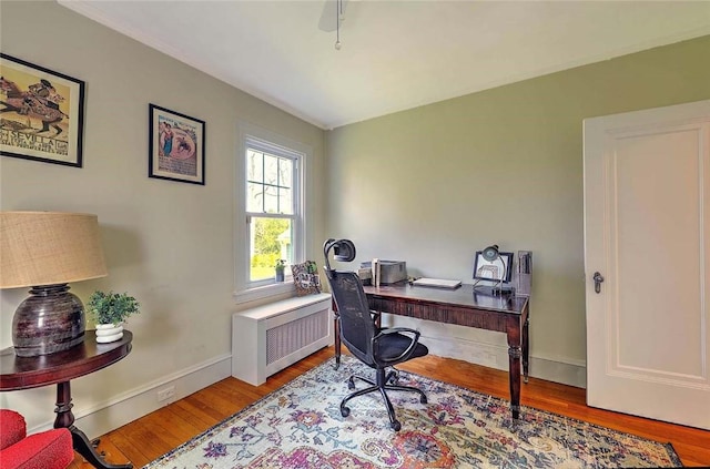 home office with wood finished floors, radiator heating unit, and baseboards