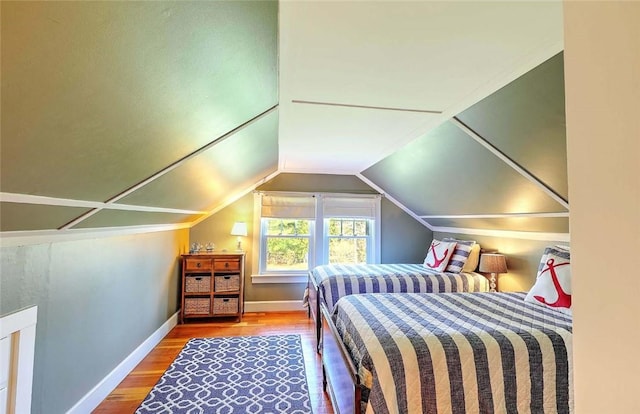 bedroom featuring baseboards, vaulted ceiling, and wood finished floors
