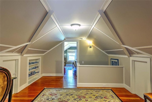 additional living space featuring built in features, wood finished floors, baseboards, and lofted ceiling