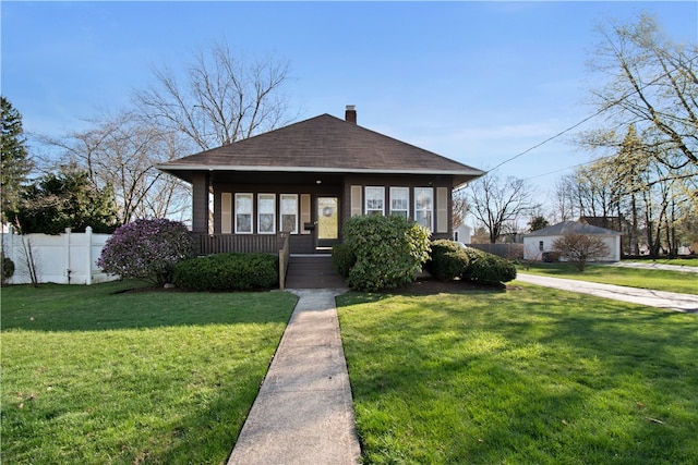 bungalow-style house featuring covered porch, a chimney, roof with shingles, fence, and a front lawn