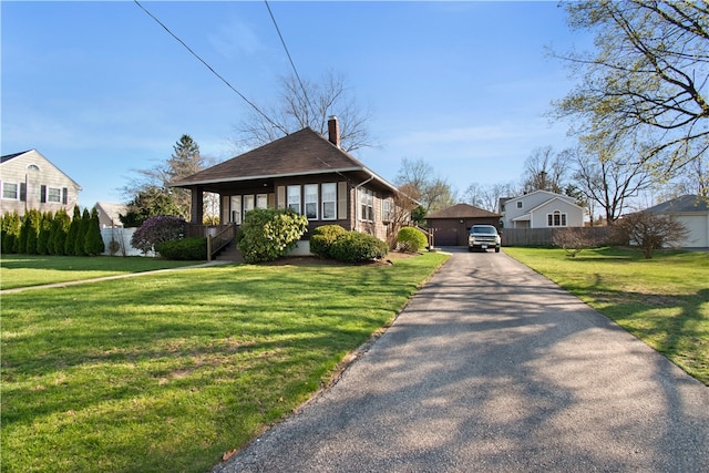 view of front of property featuring a chimney, a garage, fence, and a front yard
