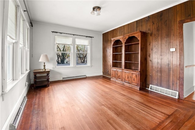 interior space with crown molding, visible vents, baseboard heating, and wood finished floors