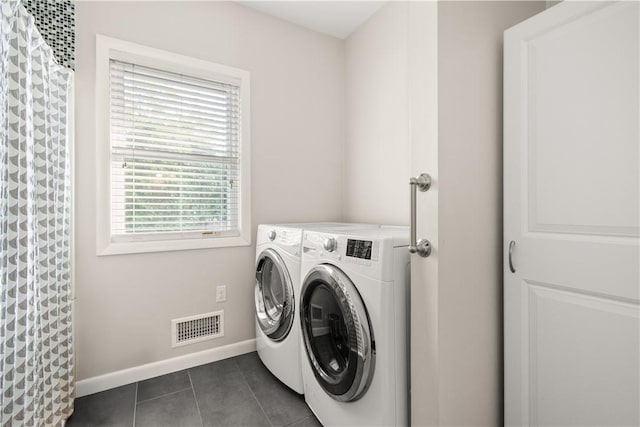 clothes washing area featuring dark tile patterned floors, laundry area, visible vents, baseboards, and washer and clothes dryer