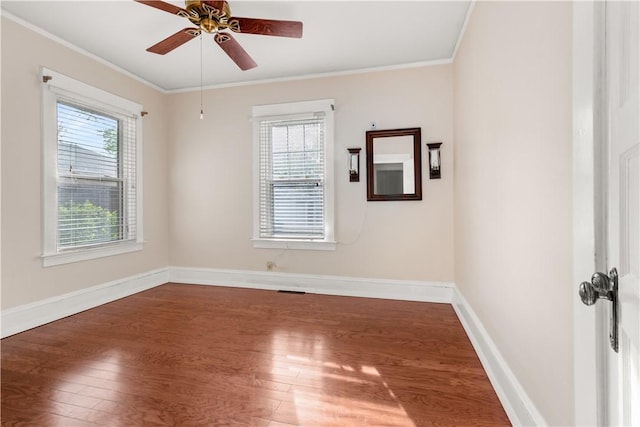 spare room featuring a healthy amount of sunlight, ornamental molding, and wood finished floors