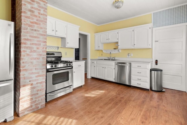kitchen with crown molding, light wood-style flooring, stainless steel appliances, and white cabinetry