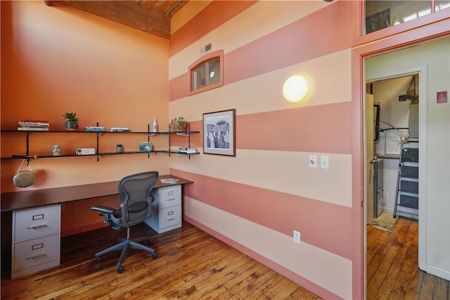 office featuring built in desk, visible vents, hardwood / wood-style flooring, and baseboards