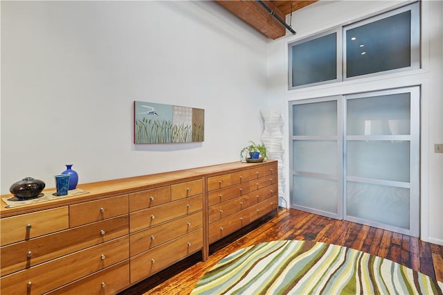bedroom with dark wood-style flooring and beam ceiling