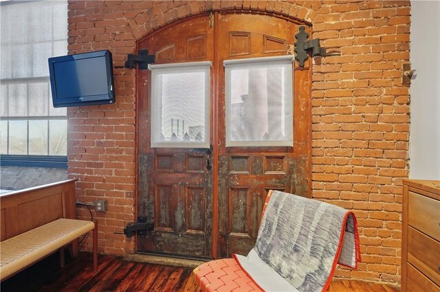 sitting room with brick wall and dark wood-style floors