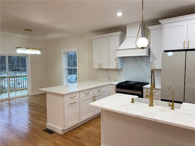 1404 Hunting Hill Dr, Cumberland, RI 02864 - kitchen featuring a peninsula, light wood-style flooring, appliances with stainless steel finishes, white cabinetry, and custom range hood