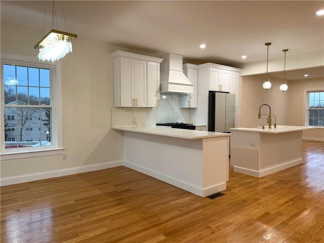 1404 Hunting Hill Dr, Cumberland, RI 02864 - kitchen with light countertops, light wood-style flooring, custom range hood, white cabinetry, and freestanding refrigerator