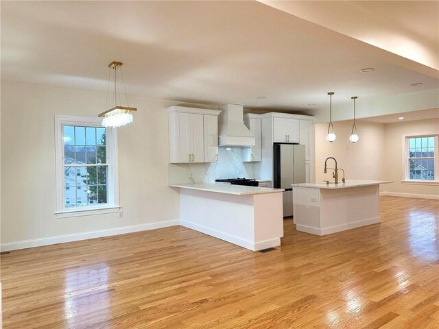 1404 Hunting Hill Dr, Cumberland, RI 02864 - kitchen featuring white cabinets, light wood-style flooring, freestanding refrigerator, light countertops, and premium range hood