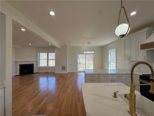 1404 Hunting Hill Dr, Cumberland, RI 02864 - kitchen featuring light wood finished floors, visible vents, recessed lighting, white cabinetry, and light stone counters
