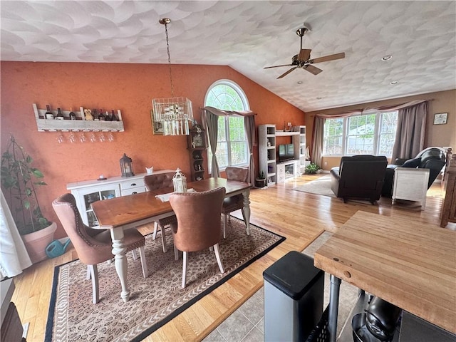 dining area with light wood finished floors, vaulted ceiling, and ceiling fan with notable chandelier