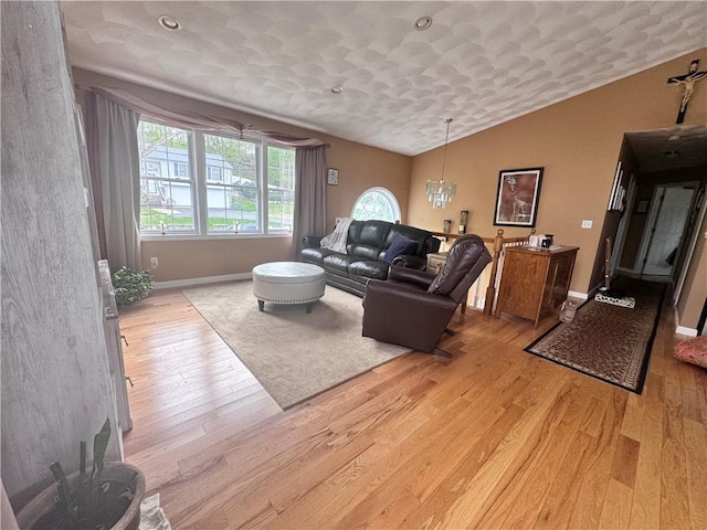 living area featuring light wood-type flooring, vaulted ceiling, and baseboards