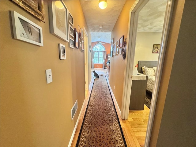 corridor with visible vents, light wood-style floors, and baseboards