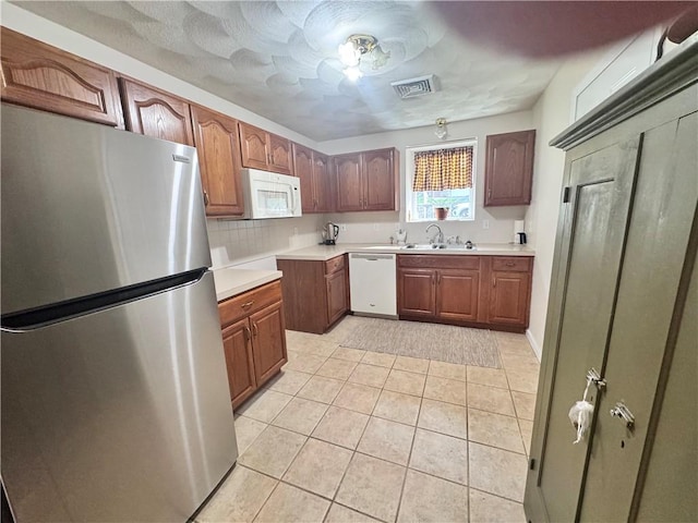 kitchen featuring light tile patterned floors, a sink, visible vents, light countertops, and white appliances