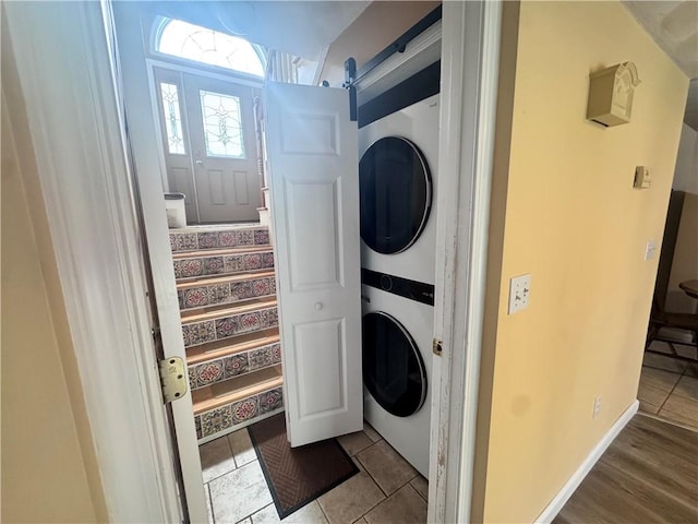 washroom with stacked washer and dryer, tile patterned flooring, and laundry area