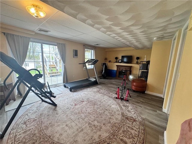exercise area featuring visible vents, wood finished floors, and baseboards