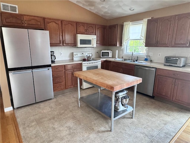 kitchen with backsplash, appliances with stainless steel finishes, light countertops, and a sink