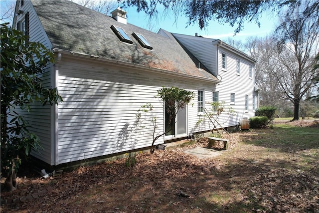 23 Rockland Dr, South Kingstown, RI 02879 - view of side of property with a shingled roof and a chimney
