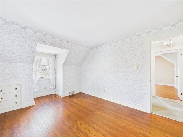 23 Rockland Dr, South Kingstown, RI 02879 - additional living space featuring visible vents, wallpapered walls, wood finished floors, and lofted ceiling