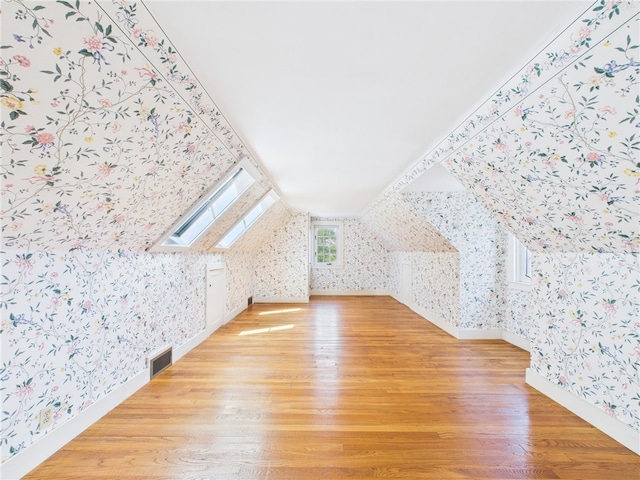 23 Rockland Dr, South Kingstown, RI 02879 - bonus room with visible vents, baseboards, wood finished floors, wallpapered walls, and lofted ceiling