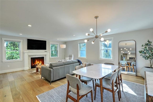 137 Rosebriar Ave, South Kingstown, RI 02879 - dining space with a healthy amount of sunlight, light wood finished floors, an inviting chandelier, and a warm lit fireplace