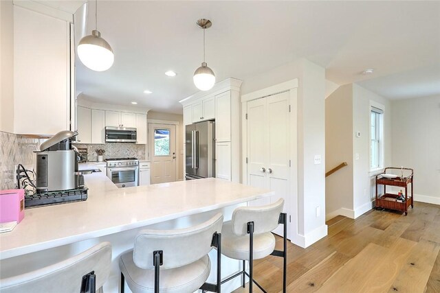 137 Rosebriar Ave, South Kingstown, RI 02879 - kitchen with premium appliances, a peninsula, light wood-style flooring, and light countertops