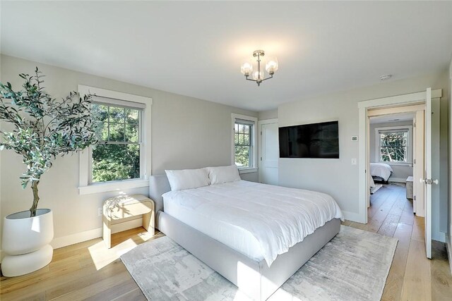 137 Rosebriar Ave, South Kingstown, RI 02879 - bedroom with baseboards, light wood finished floors, multiple windows, and an inviting chandelier