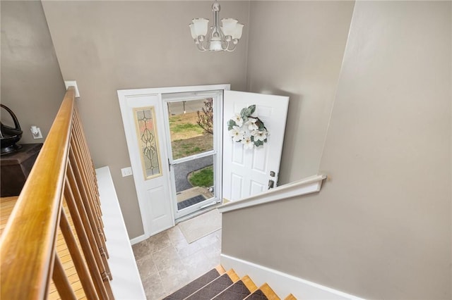 foyer featuring baseboards, stairway, an inviting chandelier, and a towering ceiling