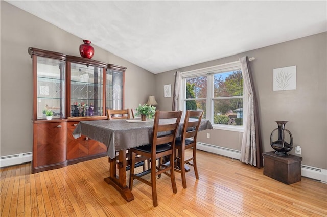 dining room featuring a baseboard heating unit, light wood-style flooring, and vaulted ceiling
