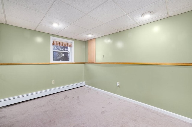 finished below grade area with carpet, baseboards, baseboard heating, and a paneled ceiling