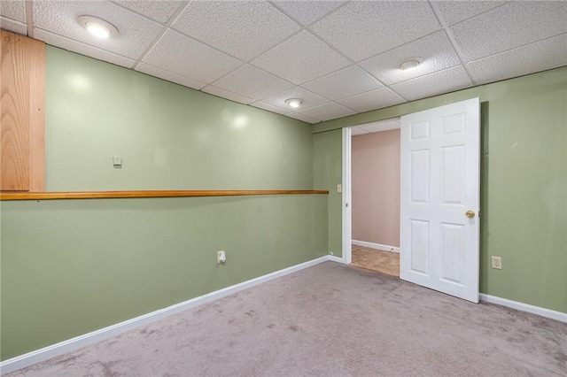 finished below grade area featuring baseboards, a paneled ceiling, and carpet floors