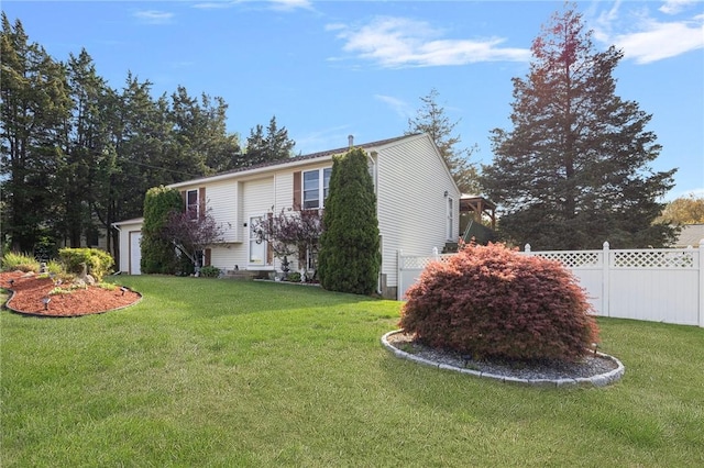 view of property exterior with an attached garage, fence, and a lawn