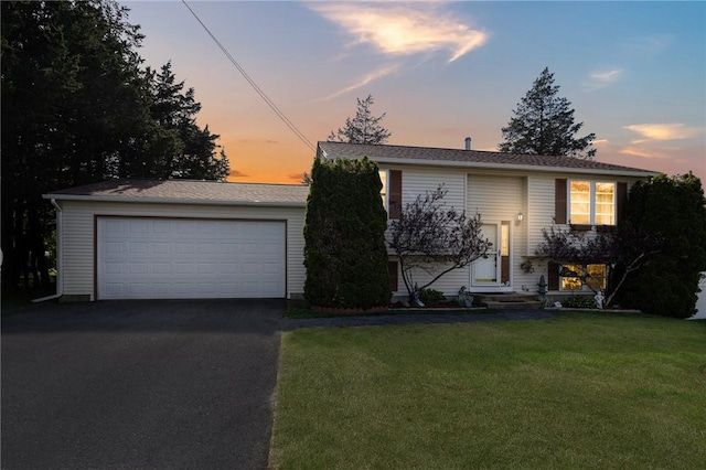 raised ranch with a lawn and a detached garage