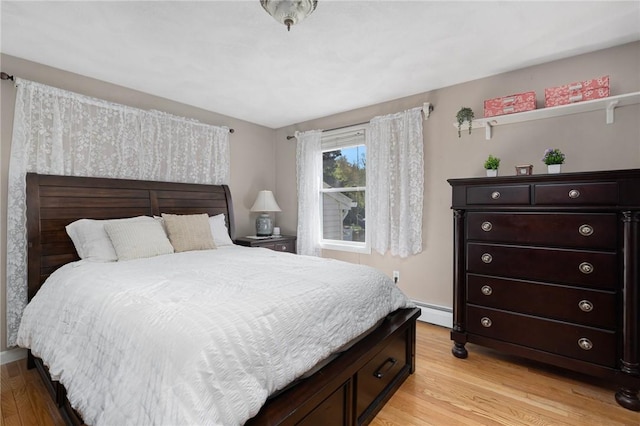 bedroom featuring a baseboard heating unit and light wood finished floors