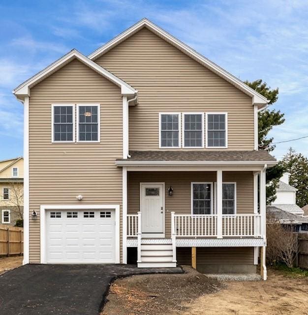 traditional-style house with a porch, driveway, a garage, and fence