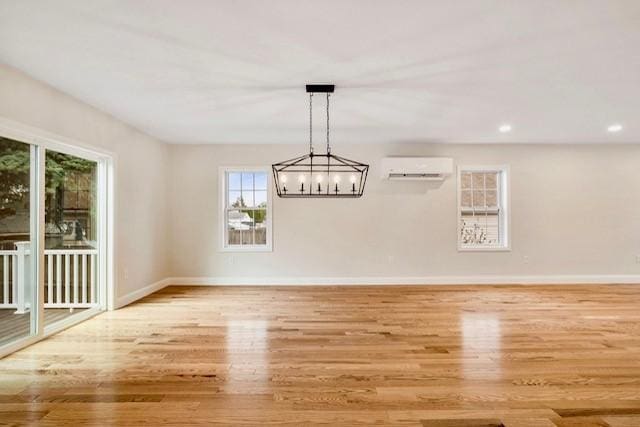 unfurnished dining area featuring baseboards, wood finished floors, and a wall mounted air conditioner