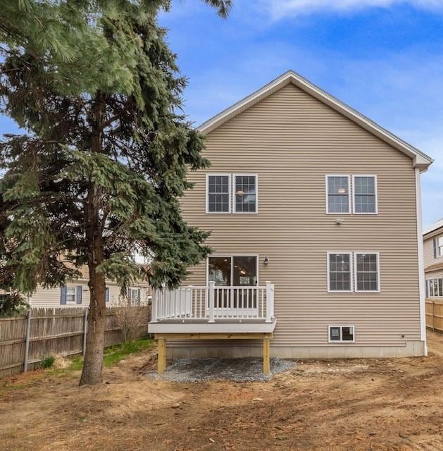 rear view of house featuring a deck and fence