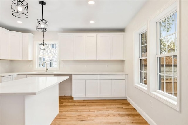 kitchen featuring a sink, light countertops, light wood finished floors, and a healthy amount of sunlight