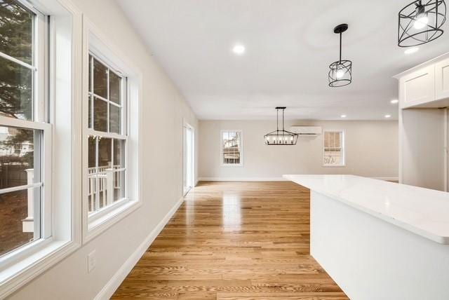 unfurnished dining area featuring a chandelier, a wall mounted AC, light wood finished floors, and recessed lighting