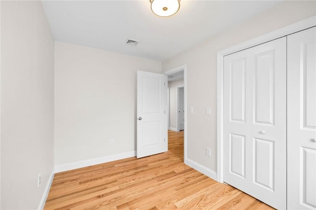 unfurnished bedroom featuring light wood-type flooring, a closet, baseboards, and visible vents