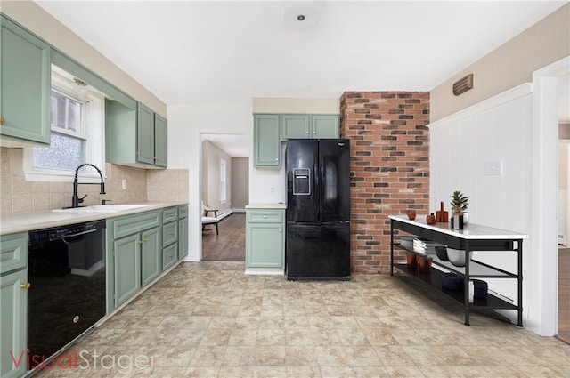 kitchen featuring tasteful backsplash, green cabinets, light countertops, black appliances, and a sink