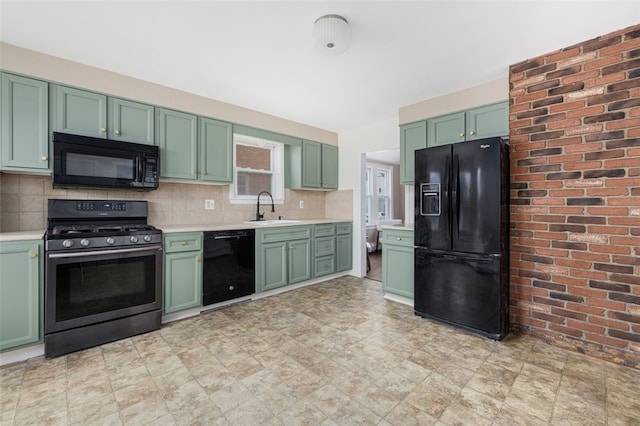kitchen with green cabinets, black appliances, light countertops, a sink, and decorative backsplash