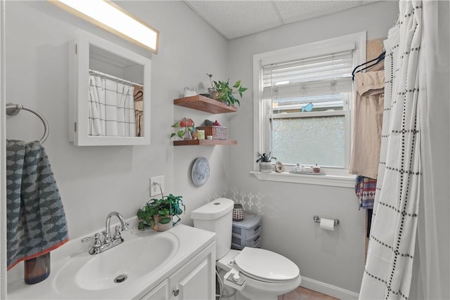 full bathroom featuring baseboards, a shower with shower curtain, toilet, a paneled ceiling, and vanity